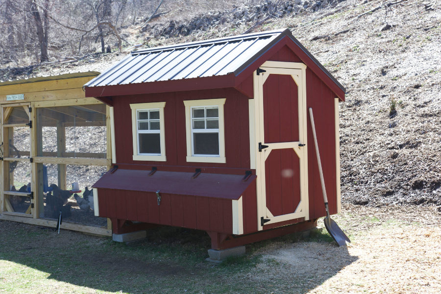 red combination chicken coop with tan trim and black metal roofing