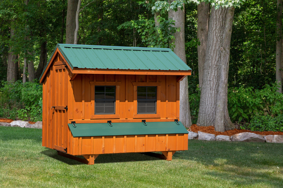 wooden quaker chicken coop with green metal roofing two large windows and an egg collection box below them with green lid