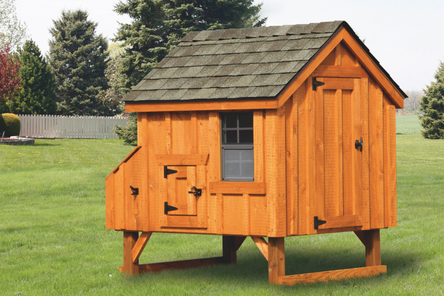 wooden a frame chicken coop with shingle roof raised off grass