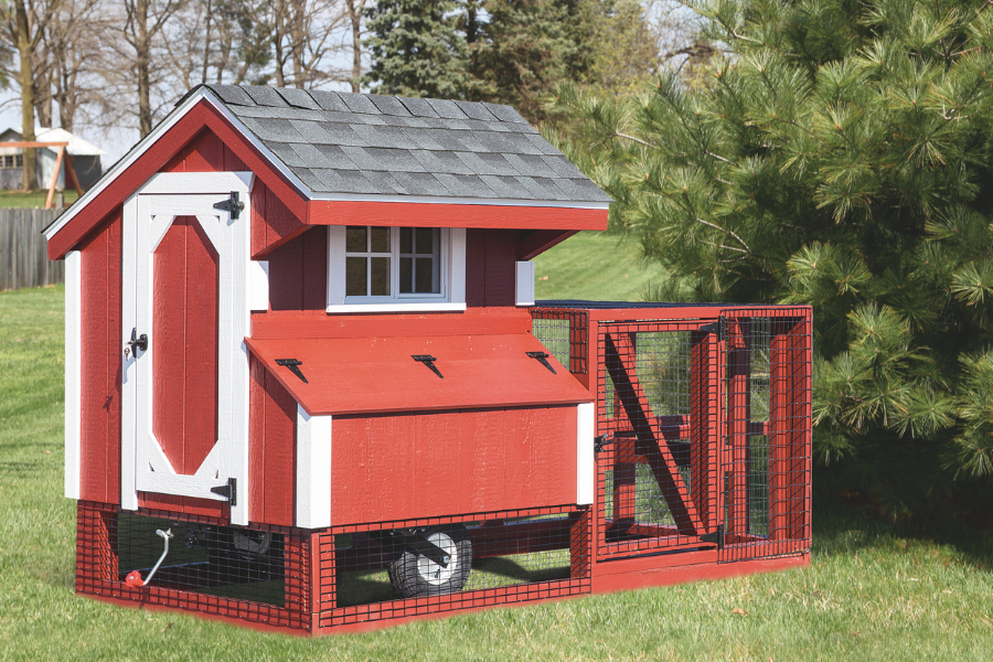 red and white trimmed tractor chicken coop with wheels attached run and gray shingle roof