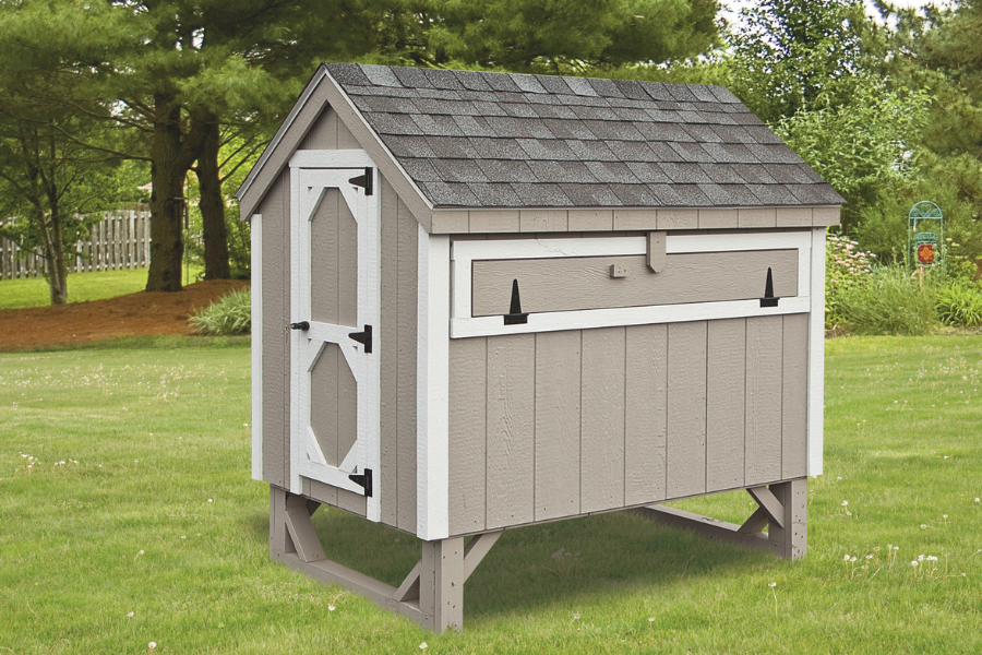 tan aframe chicken coop with white trim and shingle roof raised off of ground