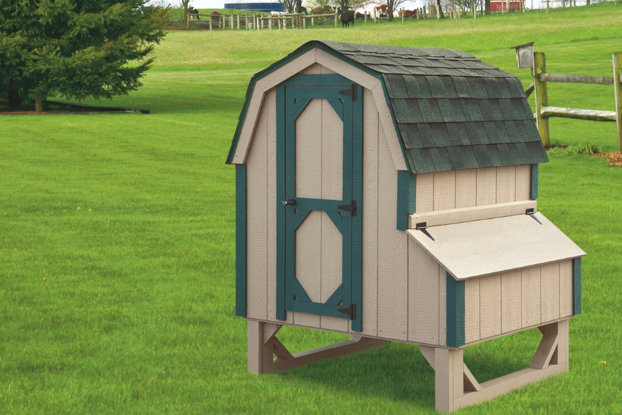 tan dutch coop with green trim curved shingle roof and egg collection box on right side raised off of ground