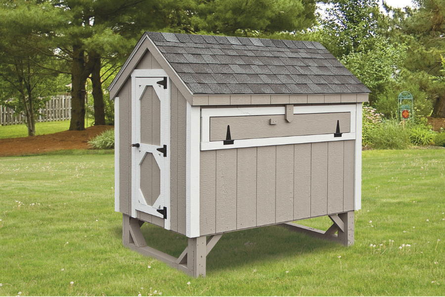 tan A frame chicken coop with white trim and shingle roof raised off ground