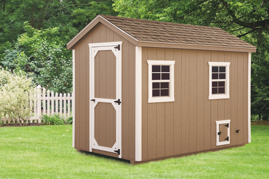 tan a frame chicken coop with white trim and brown shingle roof
