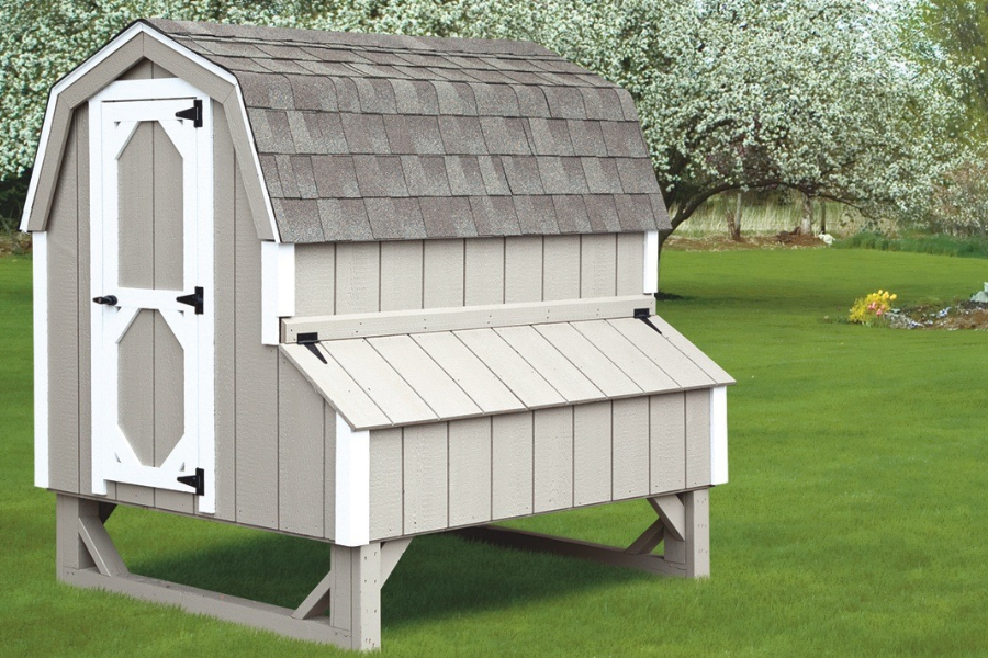 gray chicken coop with white trim egg collection box on side curved gray shingle roof slightly raised off grass