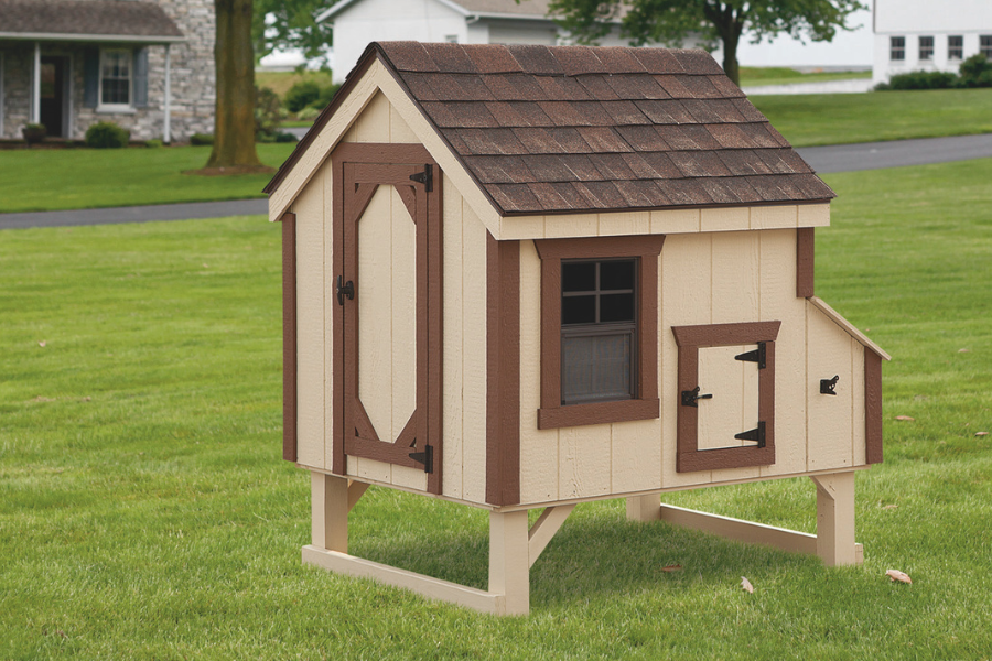 brown and tan trimmed a frame chicken coops with shingle roof side window and door slightly raised off ground