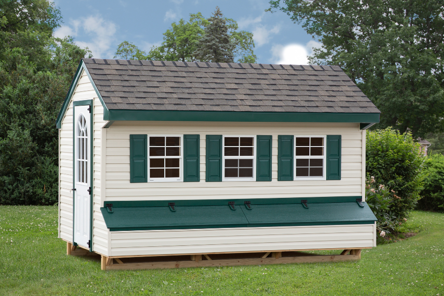 white vinyl quaker chicken coop with dark green trim three windows with two egg collection boxes below that feature dark green lids