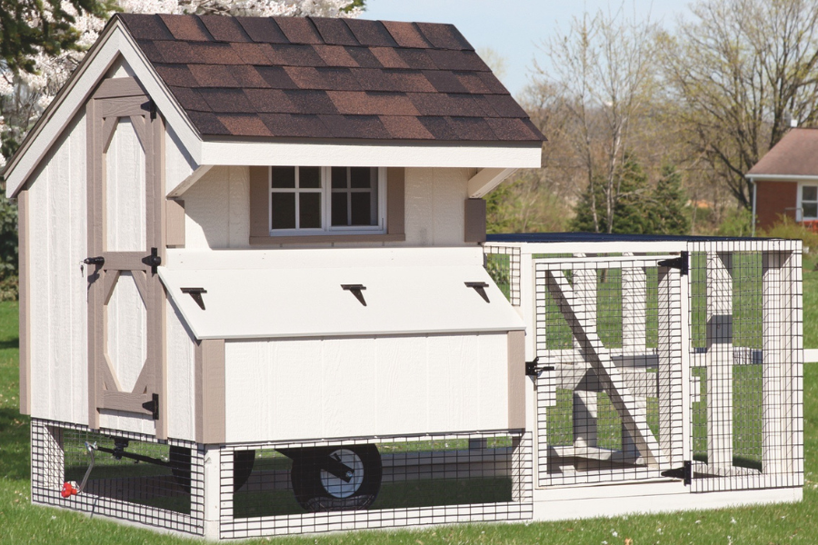 white and tan trimmed tractor chicken coop with wheels attached run and shingle roof