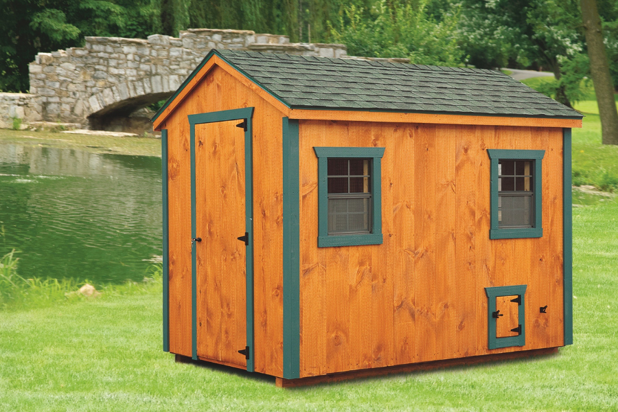 wooden a frame coop with dark green trim side door two windows and a green tinged shingle roof