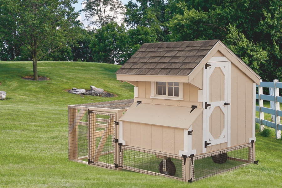 tan tractor chicken coop with white trim and an attached run and wheels