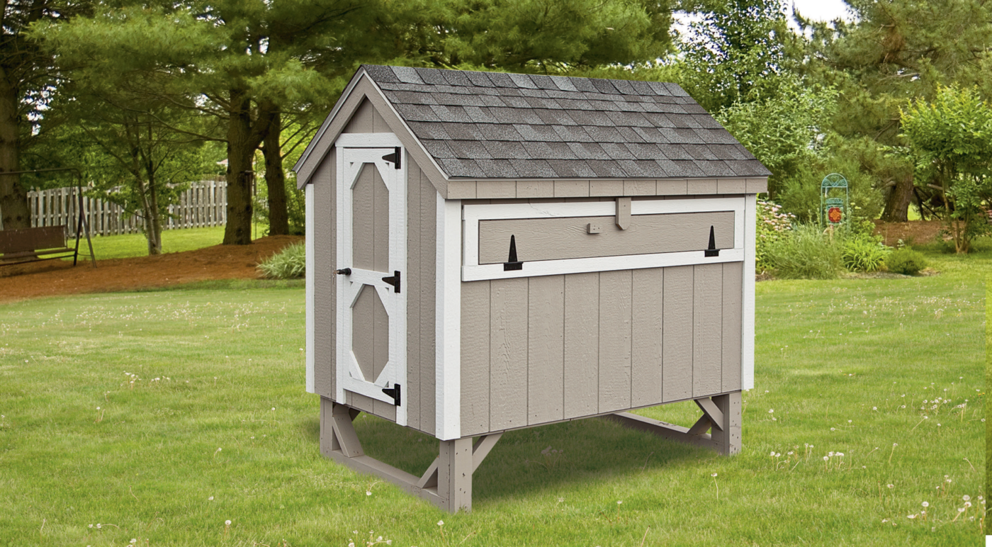An A-Frame Chicken Coop with grey siding and white trim in a green Utah yard.