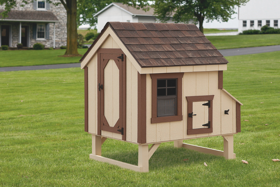tan a frame coop with brown trim and shingle roof raised slightly off ground