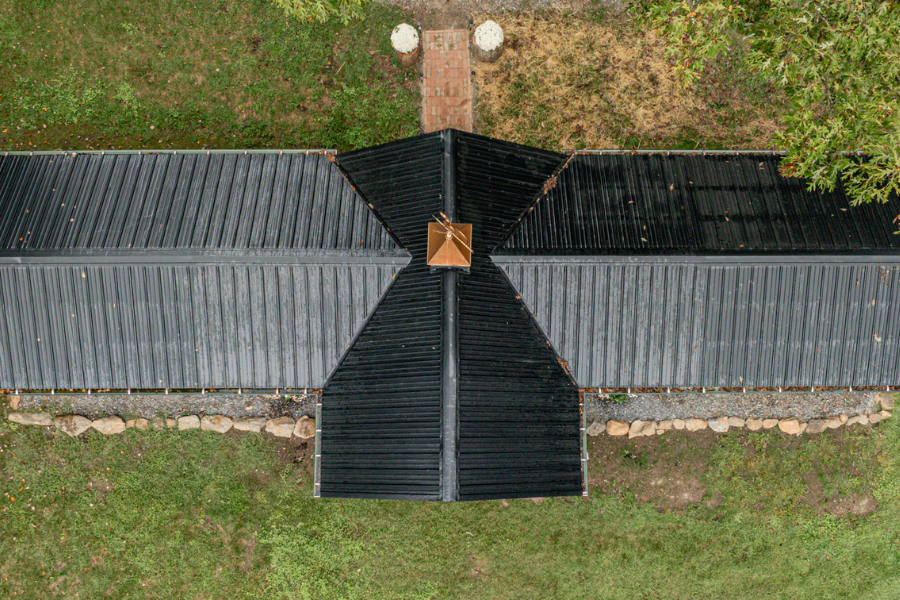 aerial view of black metal roofing on custom combination chicken coop with attached runs on either side