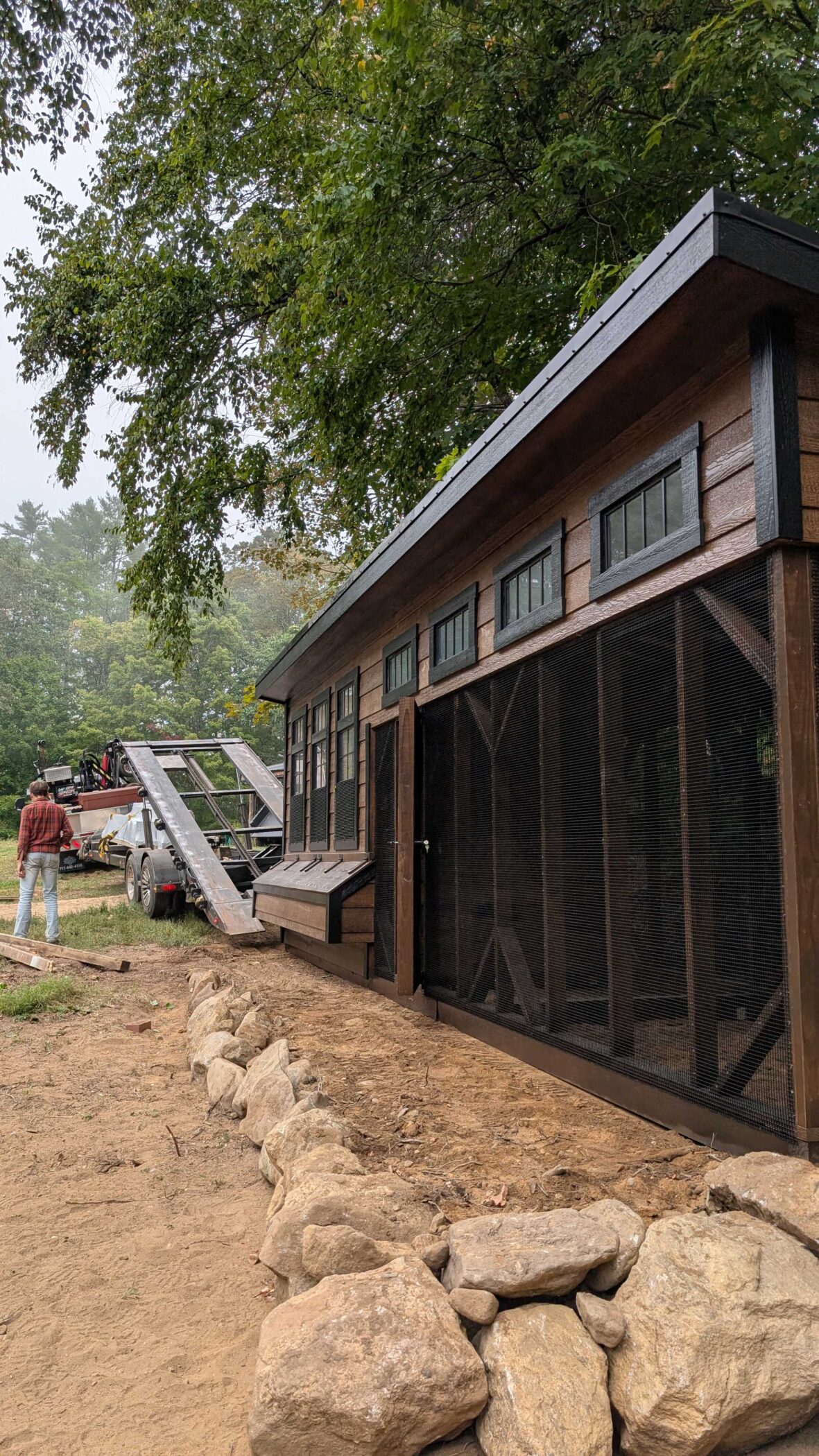 vertical image showing 7x28 chicken coop on the ground after sliding off the back of the trailer