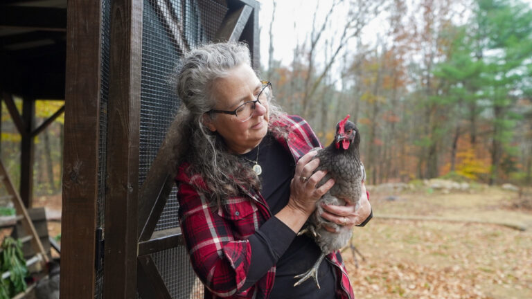 Michelle Visser holding a chicken in front of her 7x28 Lean-to Combination Coop