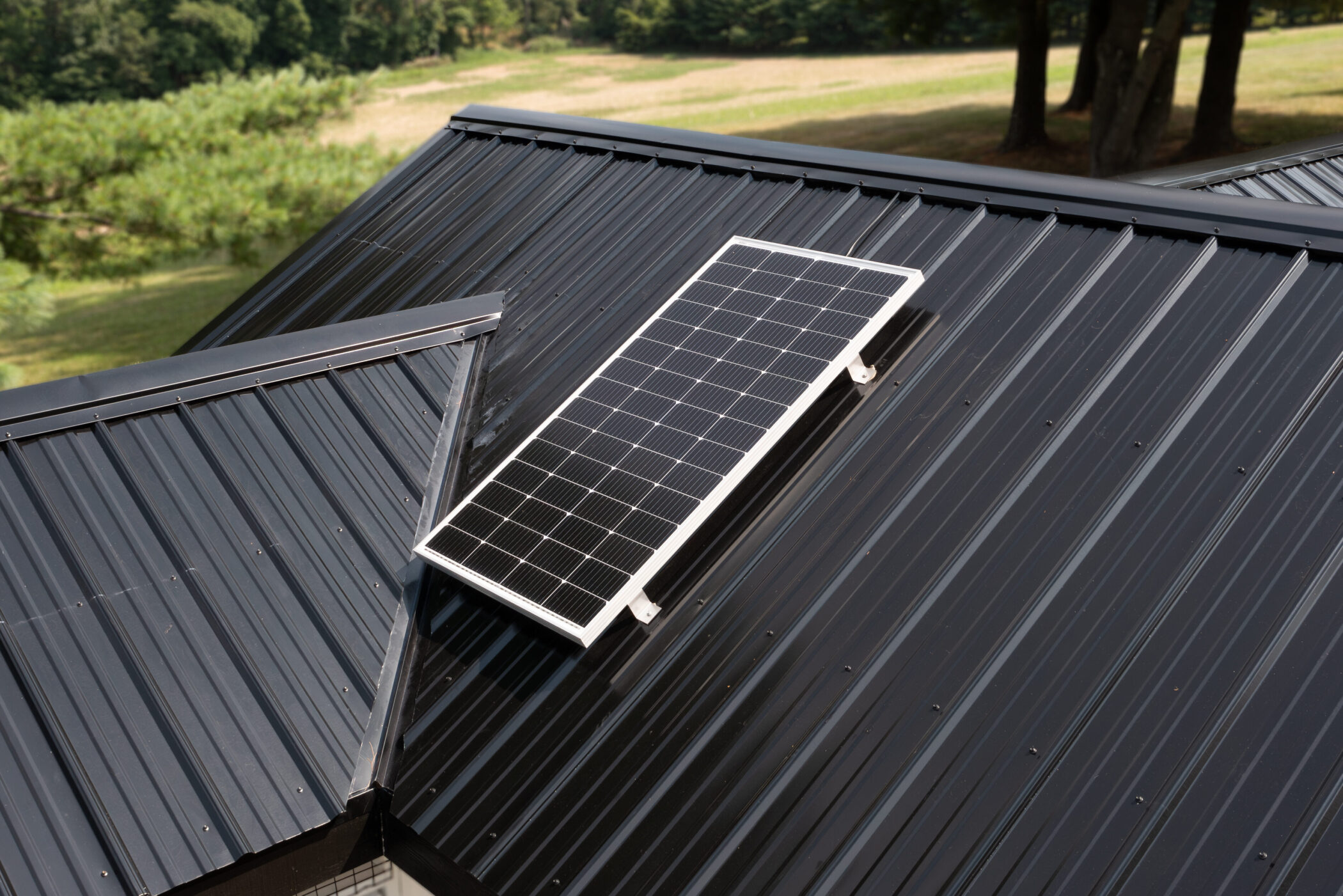 solar panel on top of black metal roof of chicken coop